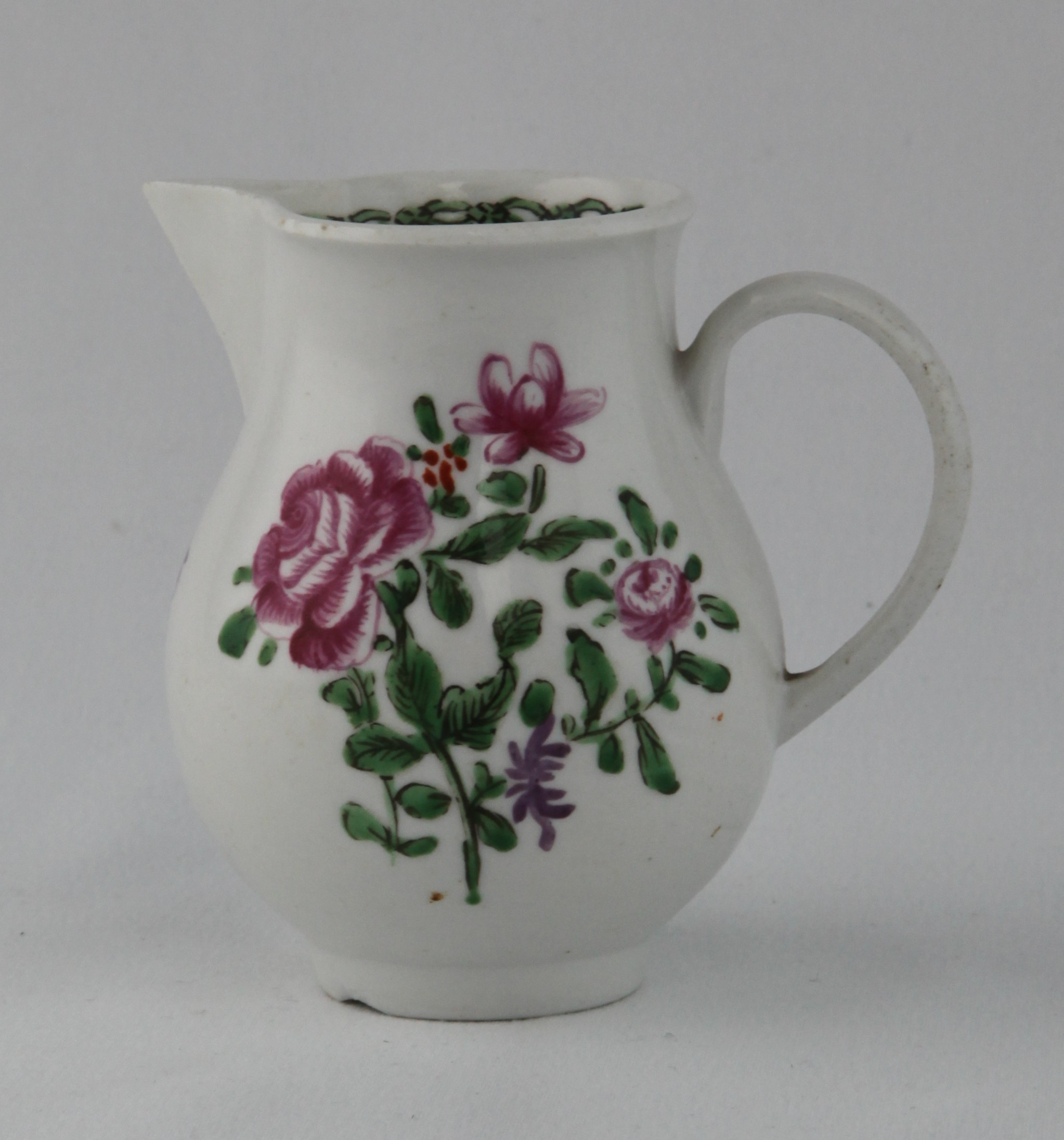 A Bristol baluster shaped sparrow beak milk jug, with loop handle, boldly painted in Chinese famille rose palette with three sprays of flowers and leaves, the interior of the rim with a green and black flower head and 'chain-link' band, circa 1775, no mark