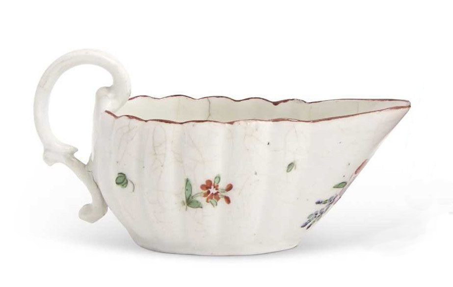 A Bristol sauceboat of fluted form and with S scroll handle, painted simply in enamels with a bouquet under the lip featuring a pink rose and two lilies, with scattered leaves and flowers under an iron red rim line, mark X22