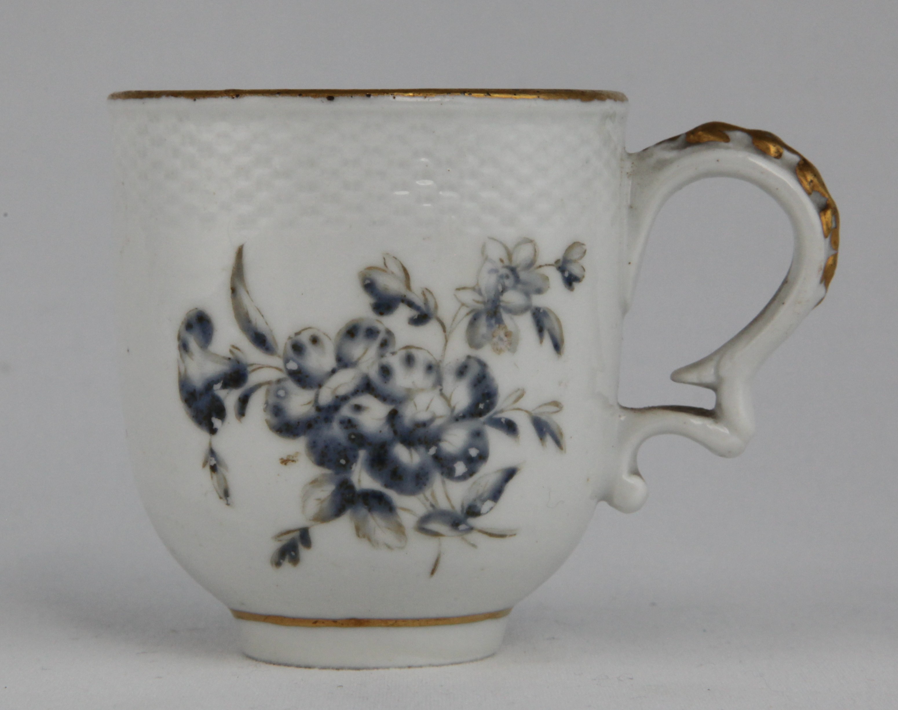 A fine Champion’s, Bristol, coffee cup with basketweave moulded border, painted in monochrome with flower sprays by James Banford. Banford was apprenticed to the Bristol factory. He became a renowned flower painter at Bristol, subsequently moving to Derby, where he also became one of the principal artists. The piece was made in the period January 1773 to August 1778. Blue "X" mark.
