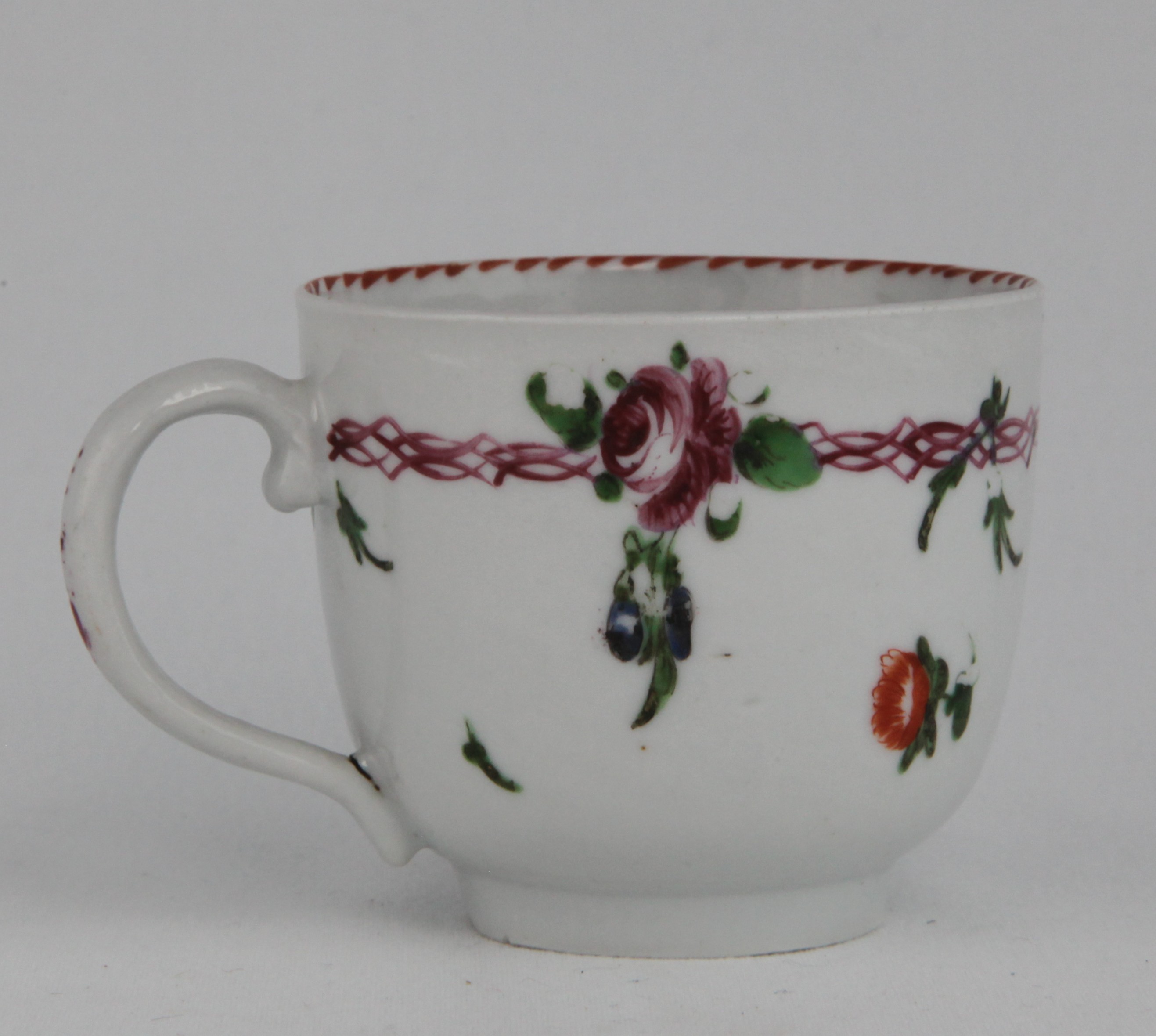 Cup, from the Pink chain service, decorated by No mark, A Bristol porcelain coffee cup with plain loop handle, painted in enamels with flowers suspended from a puce chain, and with scattered flowers, angular orange sawtooth dentil rim to the inside — Plymouth & Bristol porcelain piece 1671