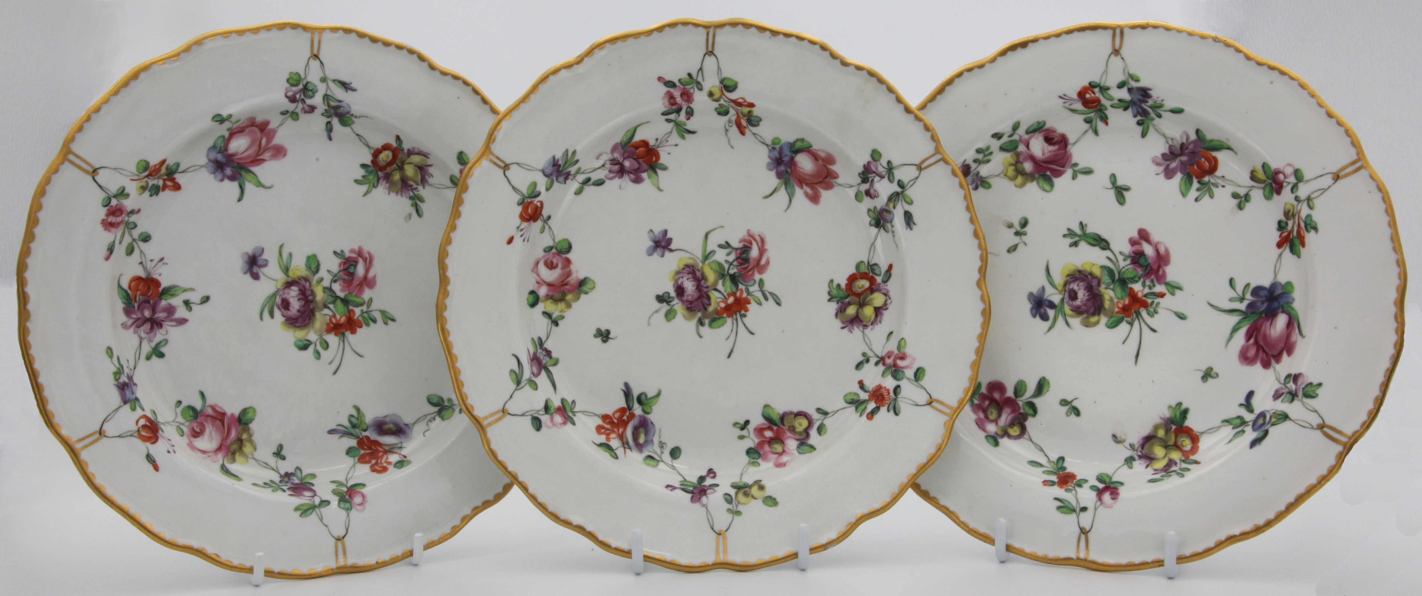 The fine lobed Bristol plates with garlands of flowers suspendend from gilt loops hanging from a gilt dentil rim.