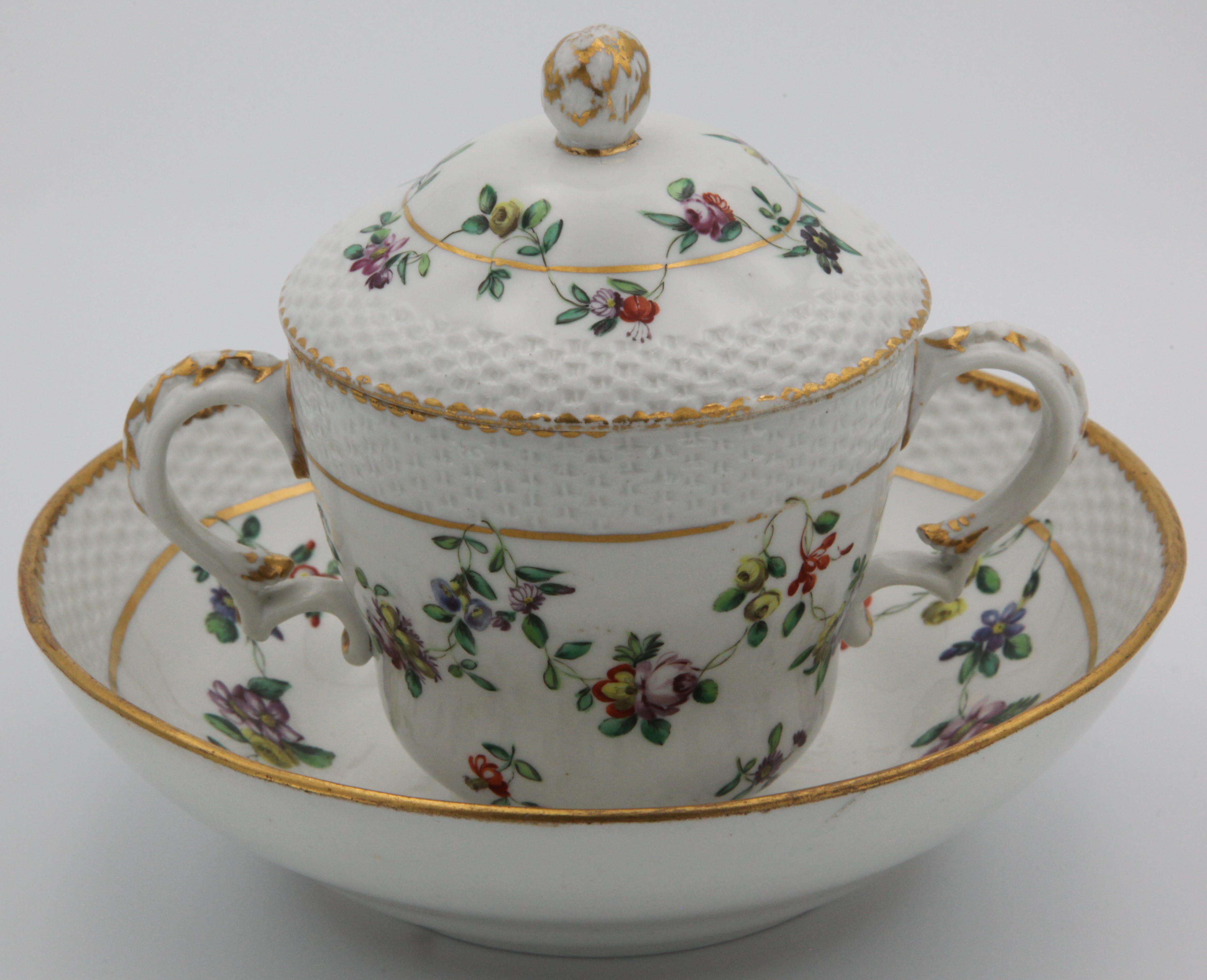A Bristol chocolate cup, cover and stand with floral garlands suspended from a gilt line