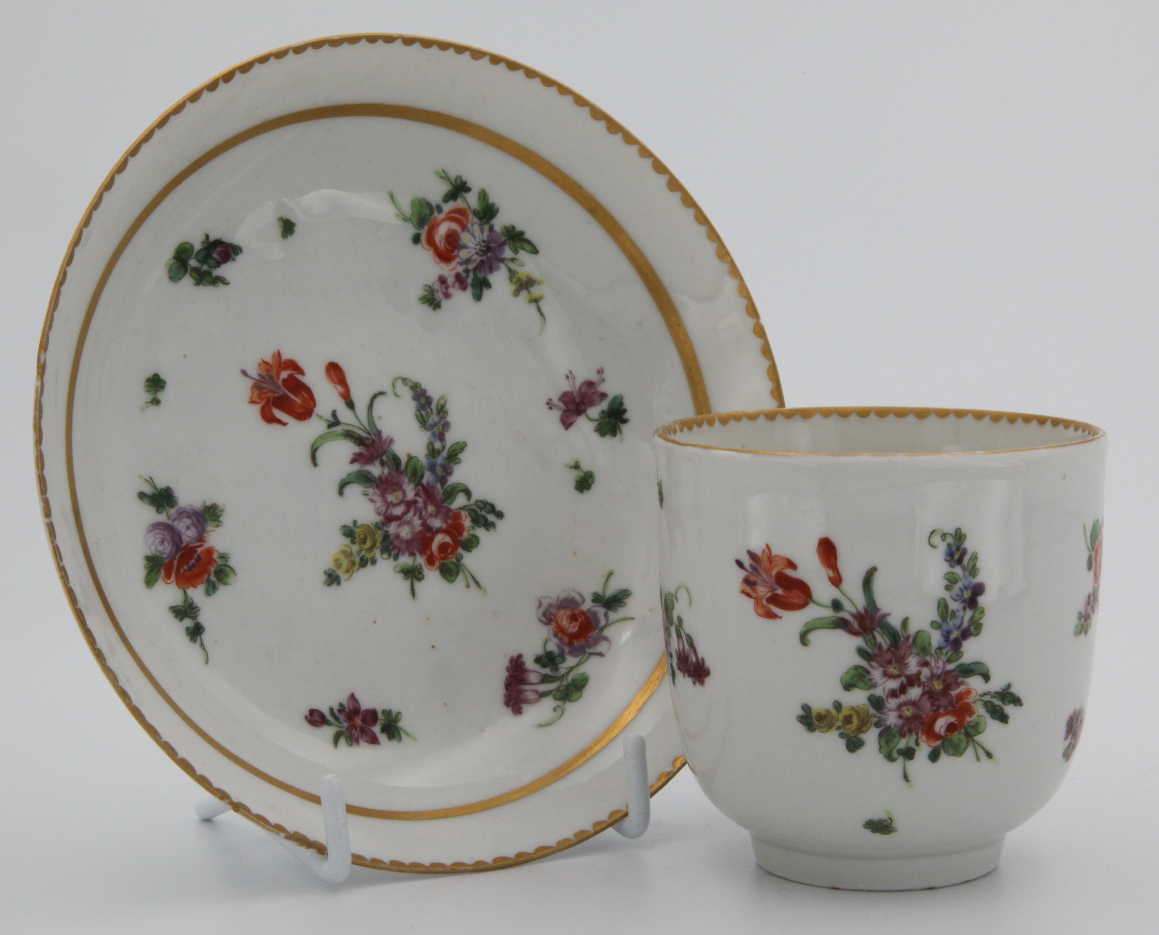 A Bristol coffee cup and saucer with thick gilt band, floral sprays and gilt dentil rim.