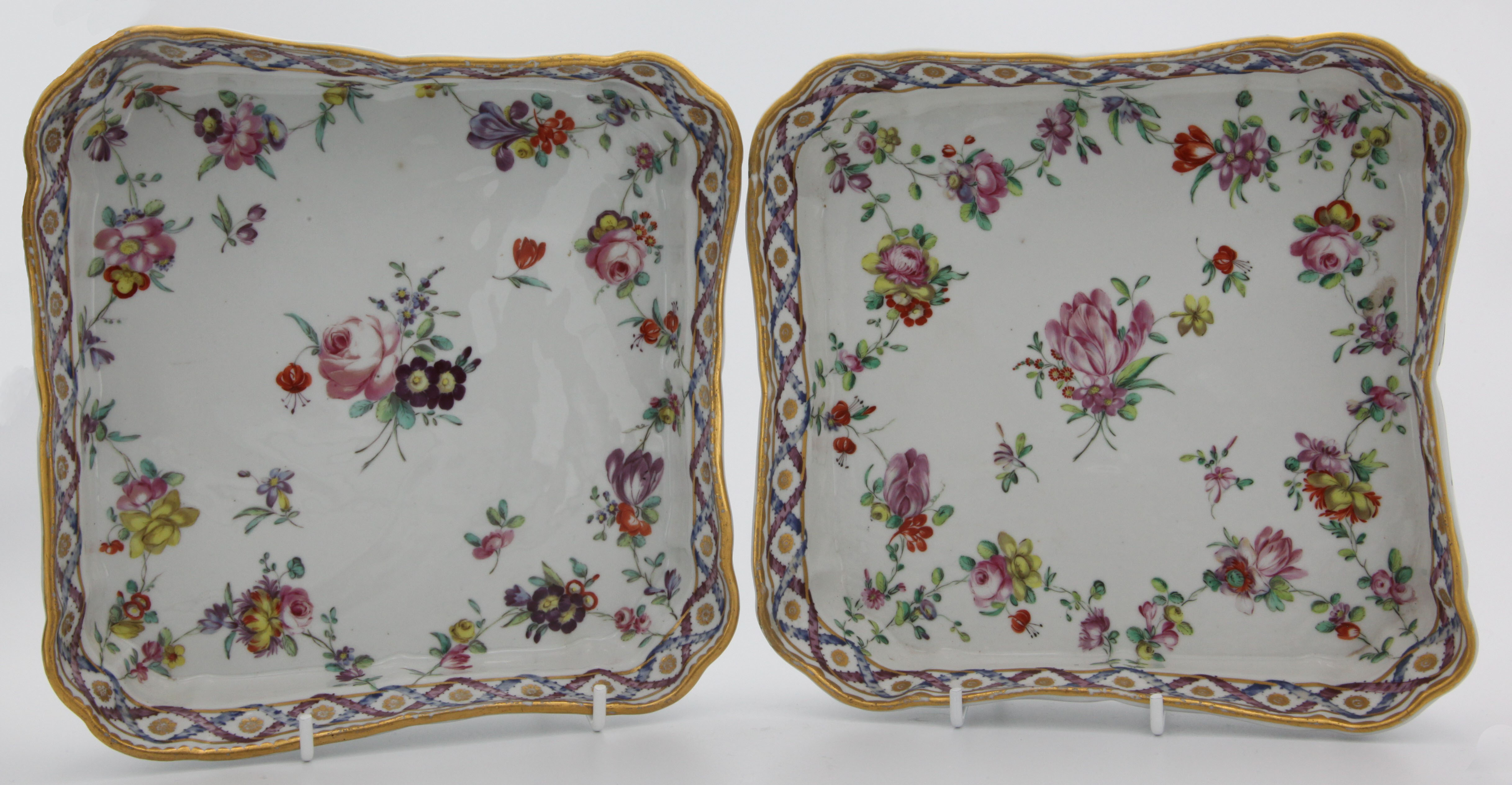 A pair of fine square Bristol dishes with garlands of flowers suspendend from gilt loops hanging from a gilt dentil rim.