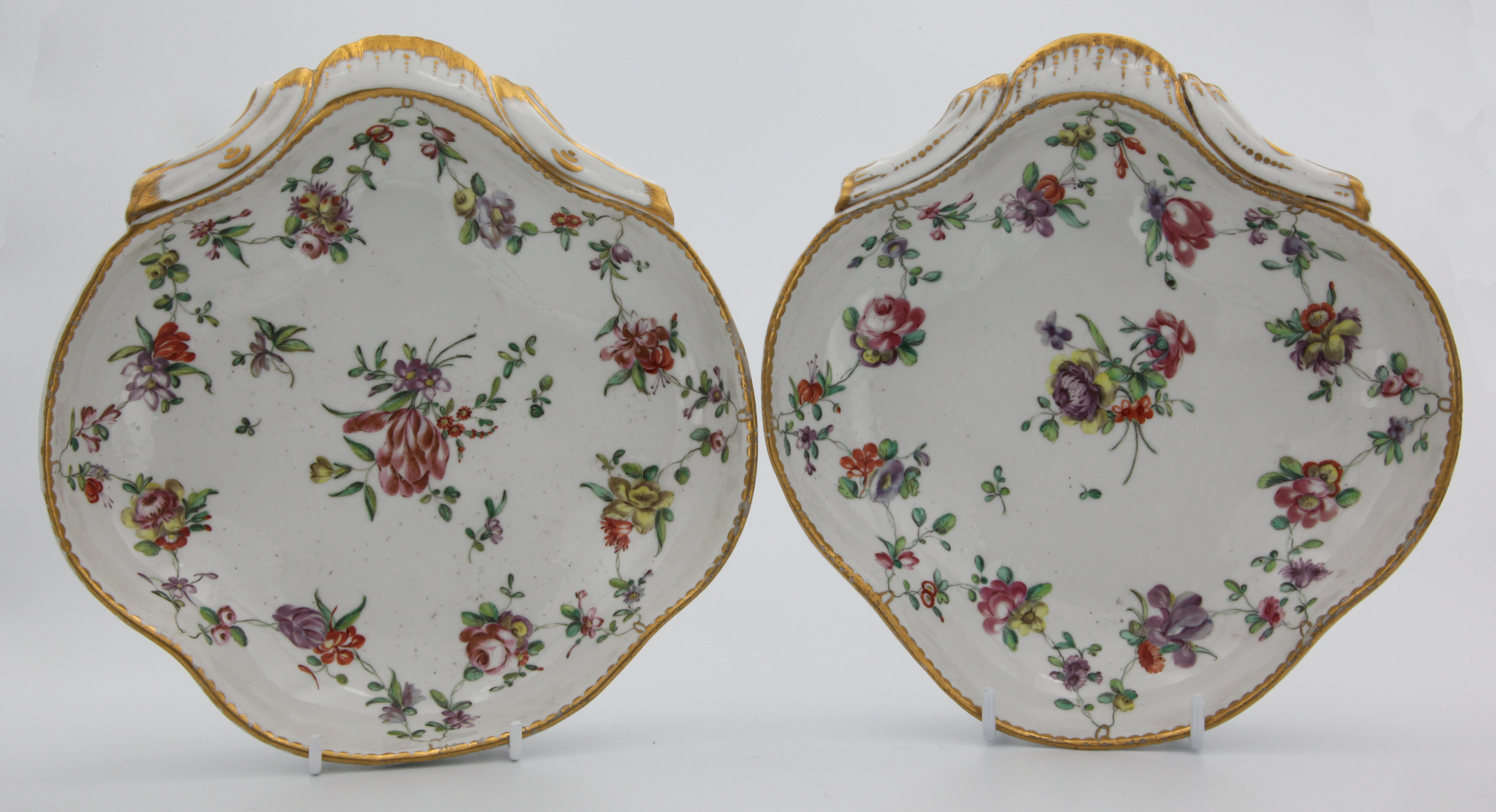 A pair of fine shell-shaped Bristol dishes with garlands of flowers suspendend from gilt loops hanging from a gilt dentil rim.