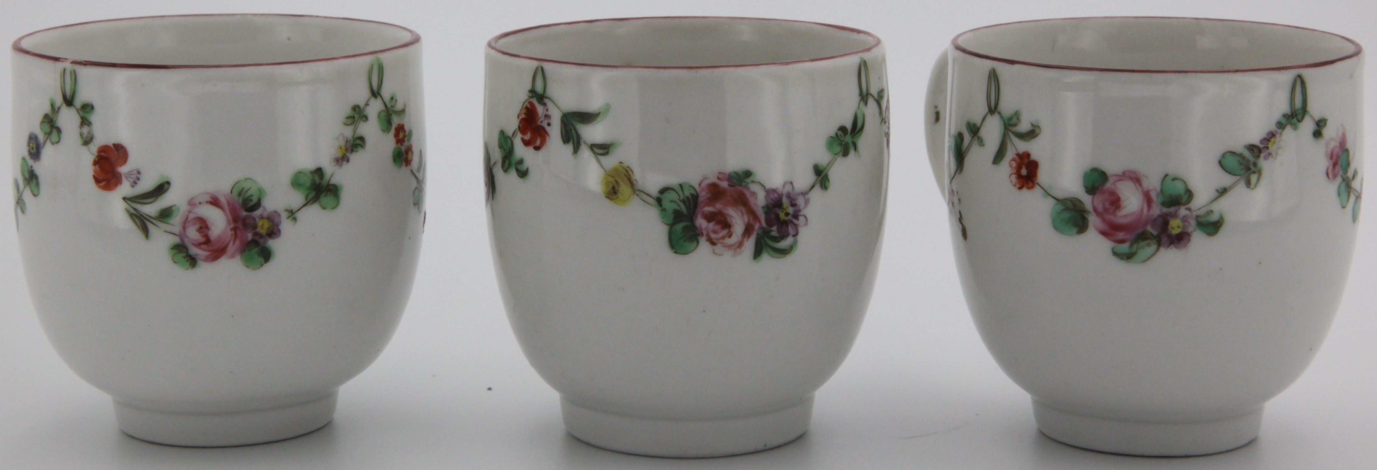 Three Bristol coffee cups with garlands of flowers suspended from green loops hanging from an iron red rim, all decorated by 16.
