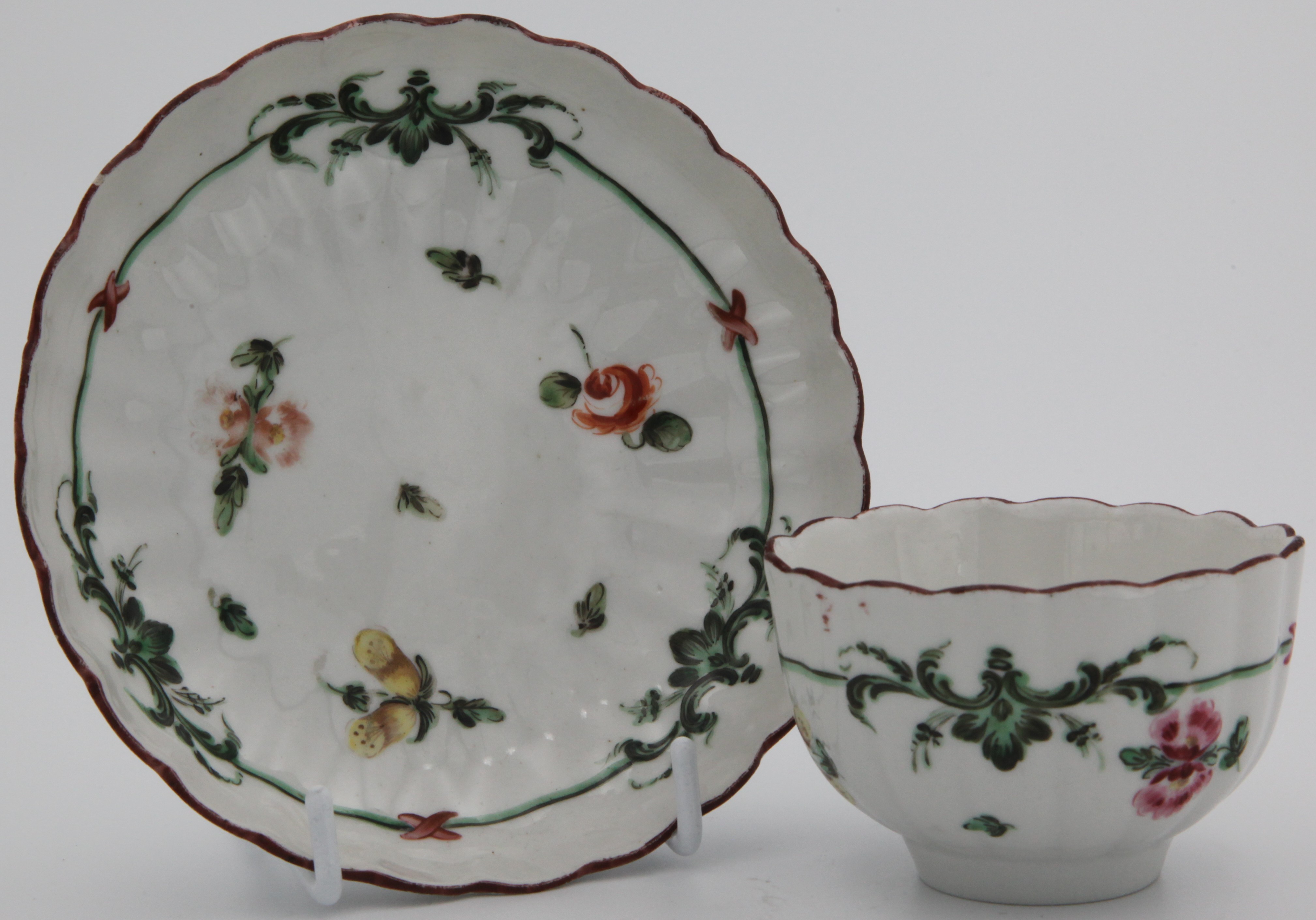 A fluted Bristol teabowl and saucer withgreen and black scroll line surrounding scattered flowers