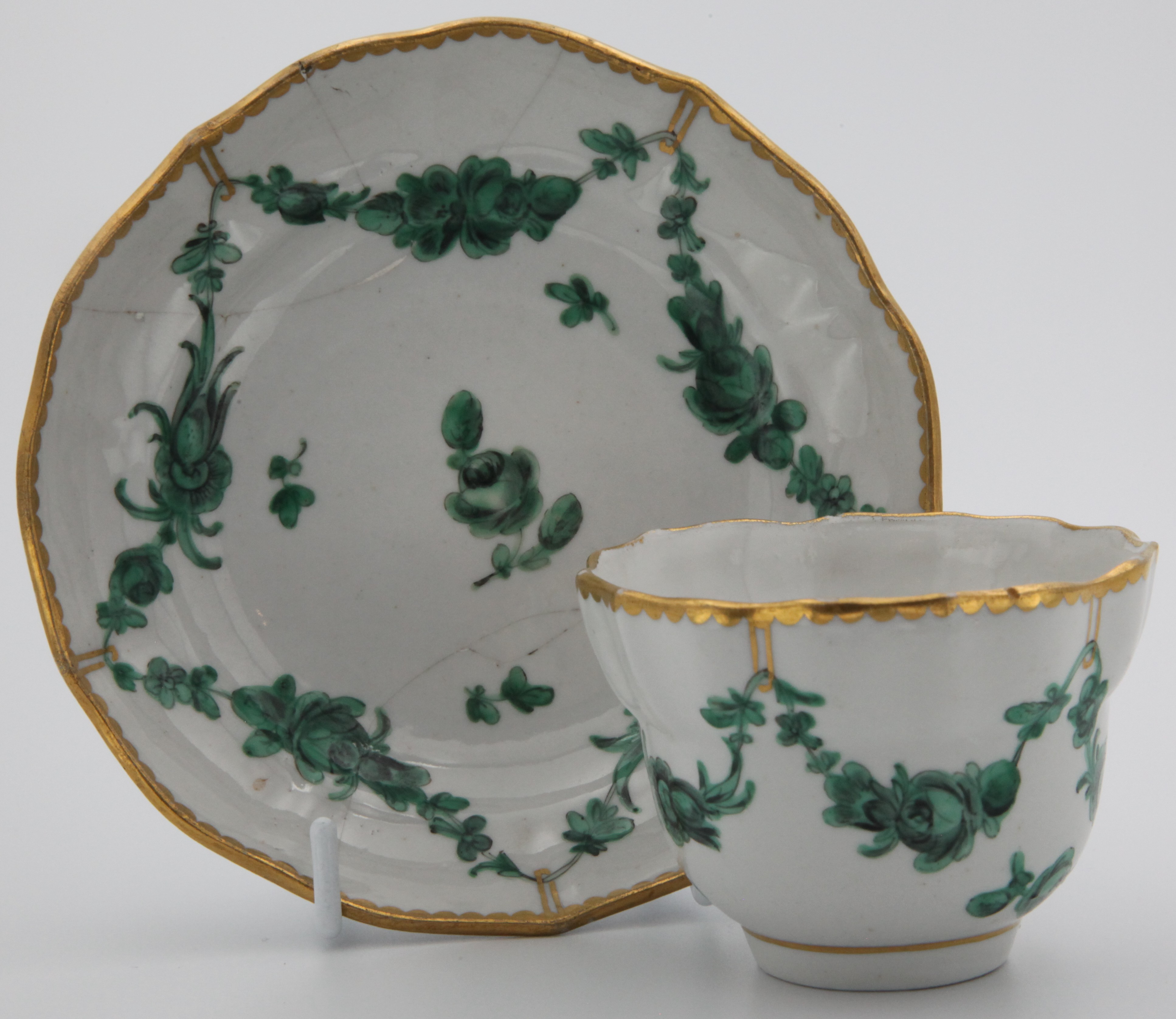 A Bristol coffee cup and saucer with green monochrome garlands suspended from loops on heavy gilt rim.