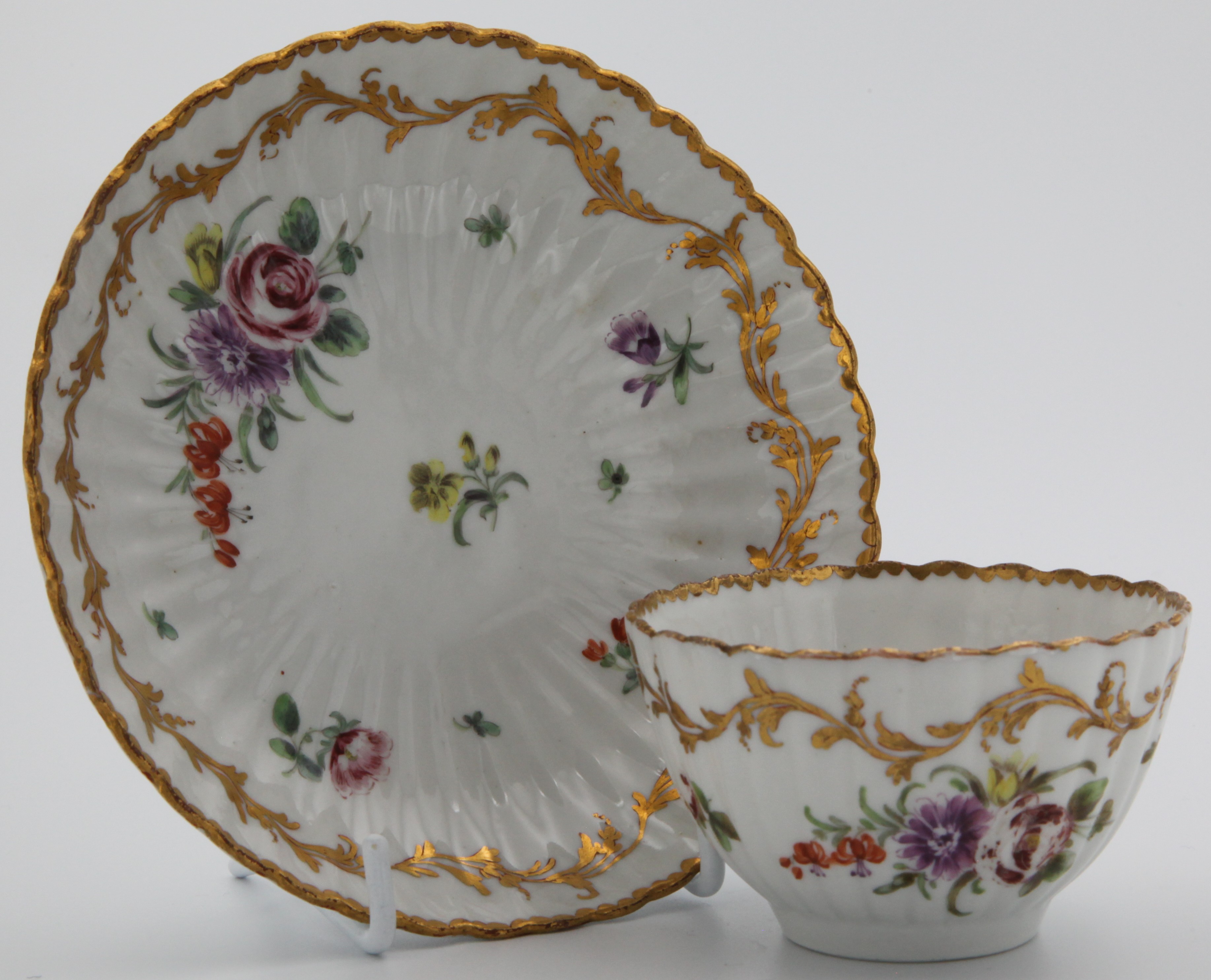 A Bristol fluted teabowl and saucer with floral sprays and leafy gilt band.
