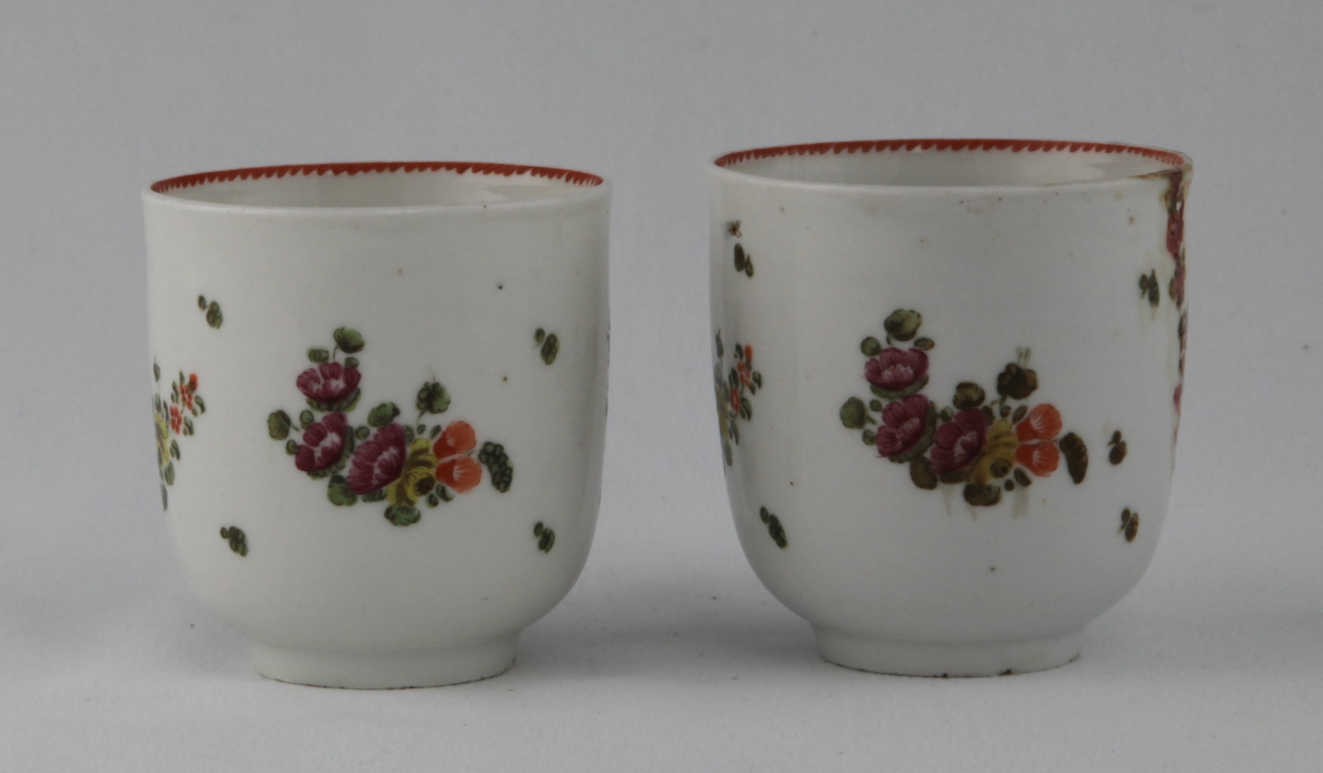 A near pair of cottage Bristol cups with scattered pink and orange flowers under an orange sawtooth rim line