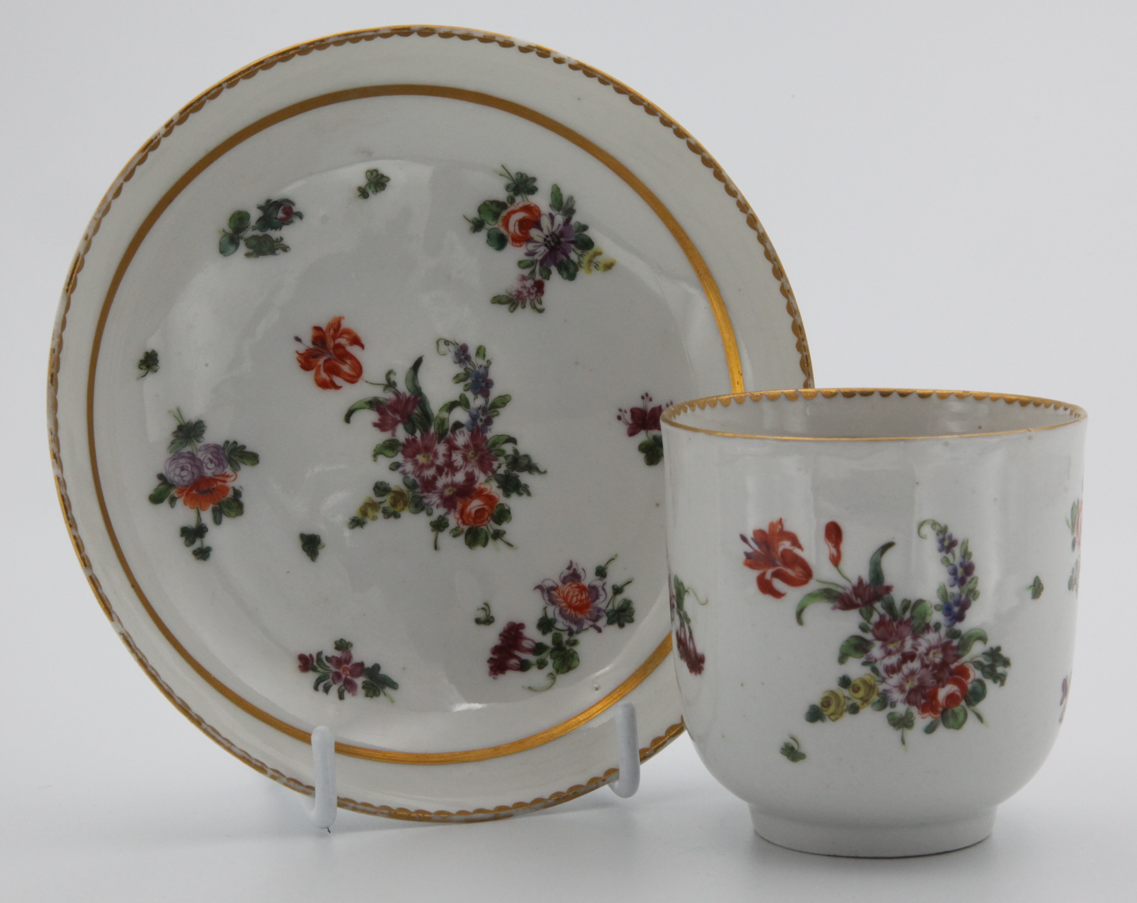 A Bristol coffee cup and saucer with thick gilt band, floral sprays and gilt dentil rim
