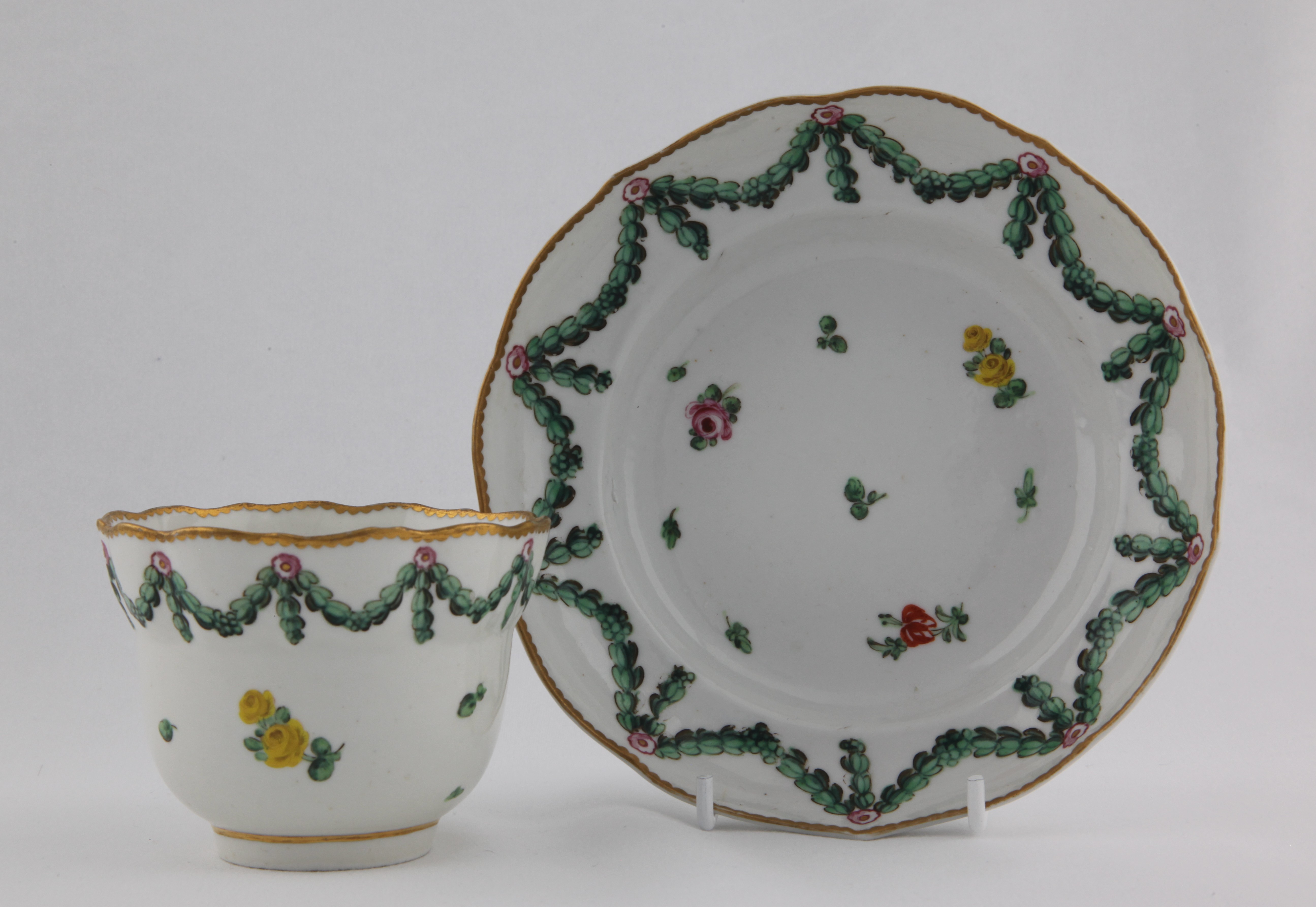 A Bristol chocolate cup and saucer with laurel garlands hanging from rose roundels